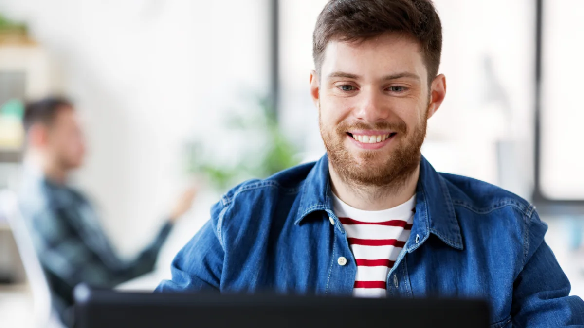 Smiling man looking at laptop in office setting